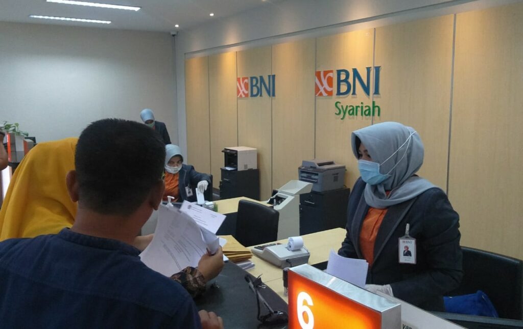 pegawai bank sedang melayani nasabah untuk keperluan menabung dll